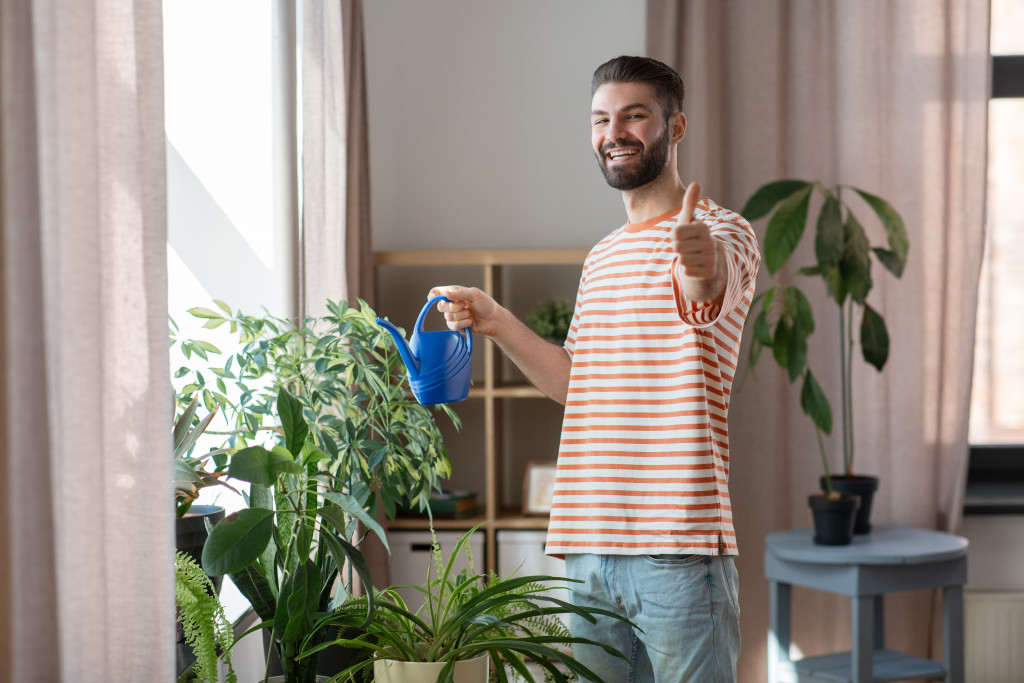 man watering his indoor plants
