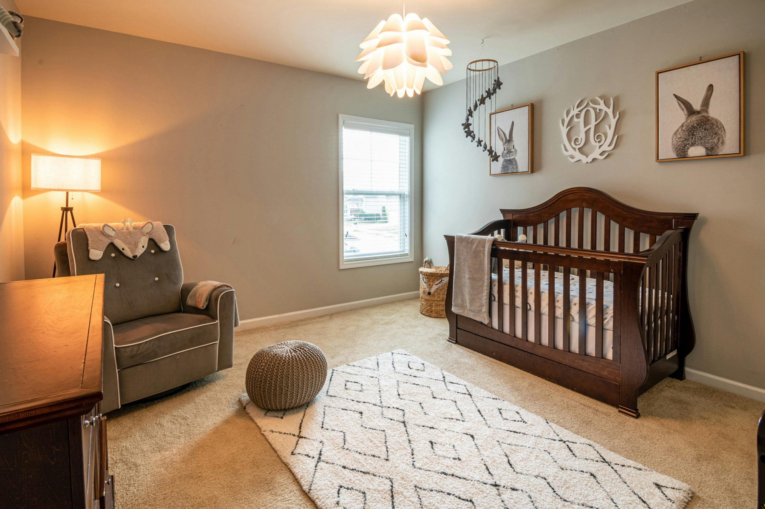 neutral-toned nursery featuring a wooden crib and a cozy recliner