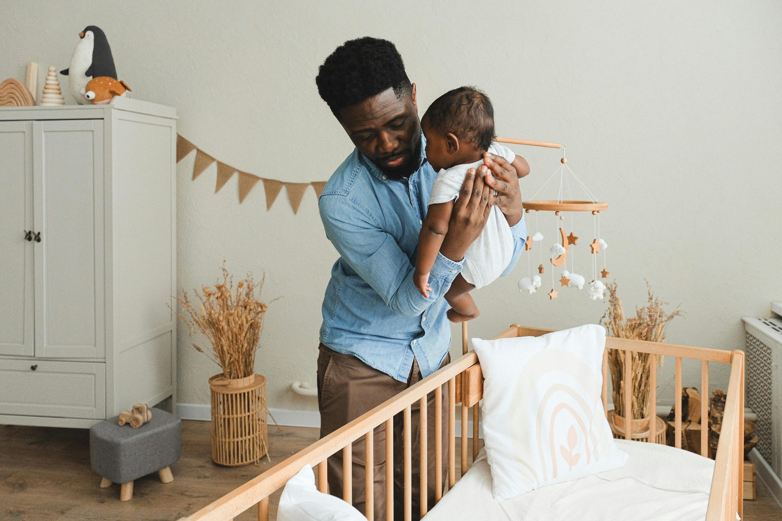 father placing his baby into a crib in a boho-themed nursery