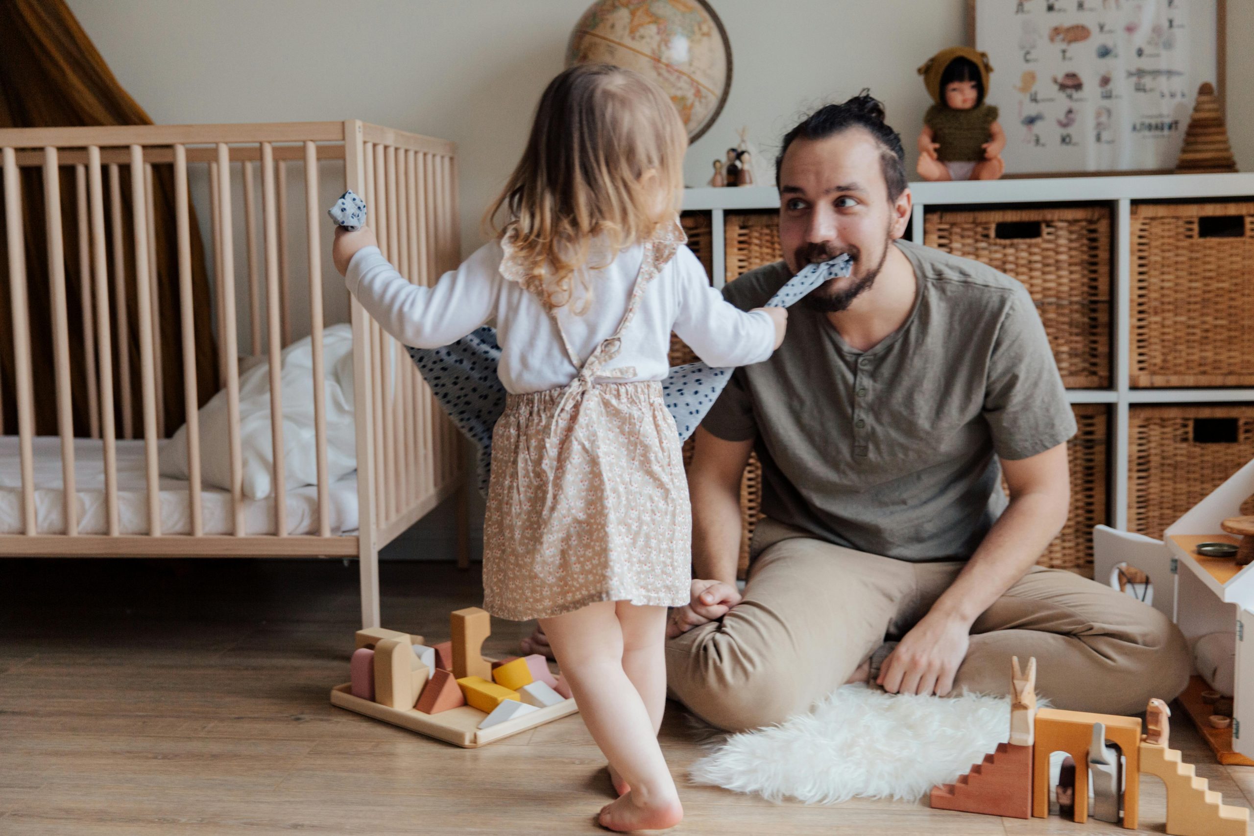 father playing with his daughter in a crowded nursery